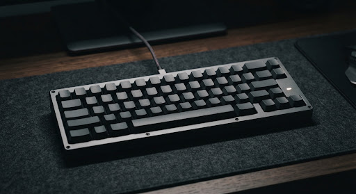 Minimalist mechanical keyboard with blank dark grey keycaps on a matte desk mat